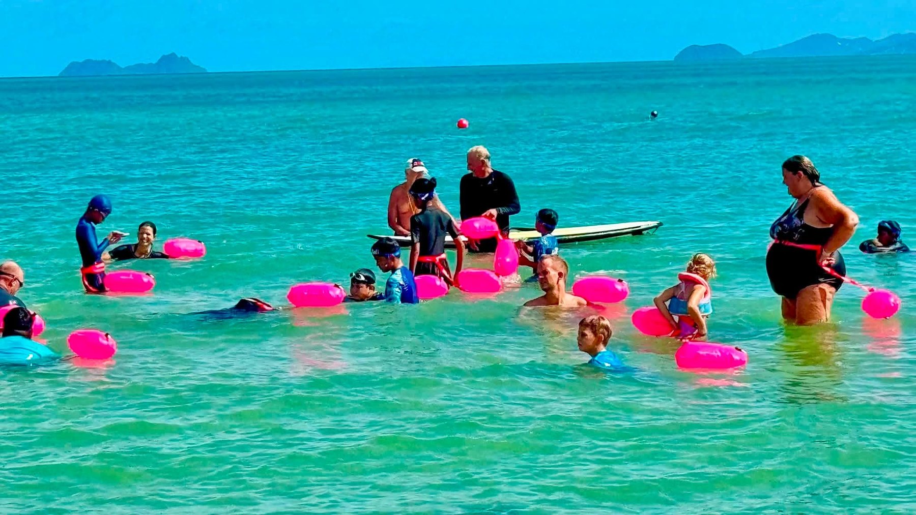Children and volunteers swimming with rescue floats